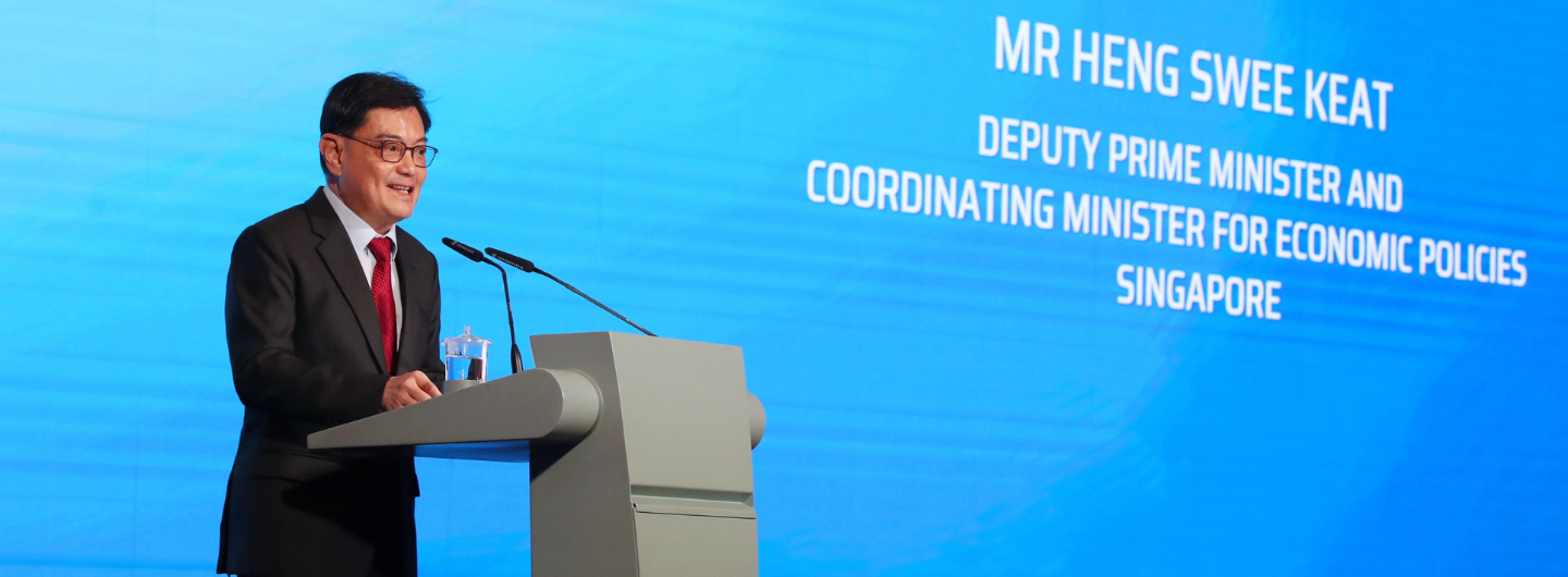 Mr. Heng Swee Keat at podium, speaking. Blue backdrop displays his title: Deputy Prime Minister, Singapore.